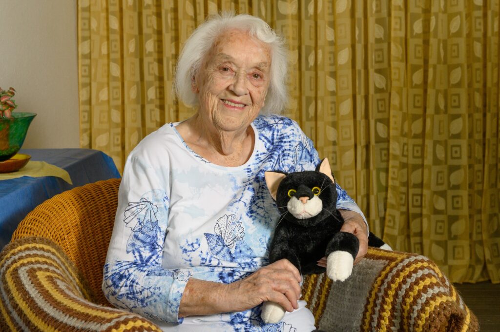 Eine ältere Dame spielt mit der RobiCare Smart Cat.
